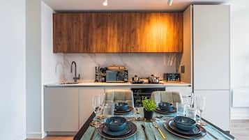 Una cocina moderna con armarios de madera, horno empotrado y comedor listo para una comida.
