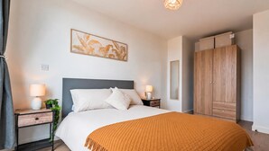 Quarto com cama, mesas de cabeceira, guarda-roupa e um quadro na parede.