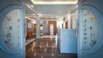 A hotel lobby with a polished floor, a reception desk, and a seating area.