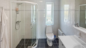 Een badkamer met een douchecabine van glas, toilet en wastafel.