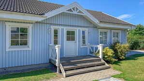Een gelijkvloers huis met een veranda, een deur en een kleine trap naar de ingang.