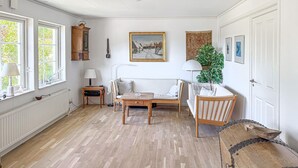 Een kamer met een bank, een tafel, een kast en een schilderij aan de muur.