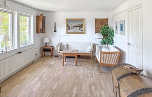 A room with a sofa, a table, a cabinet, and a painting on the wall. - 2 bedroom cozy home in Bogø By (Bogø By)