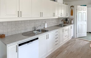 Een keuken met witte kastjes, een granieten aanrecht en een vaatwasser.