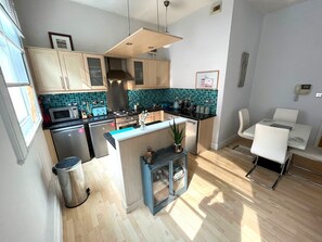 A modern kitchen with a central island, stainless steel appliances, and a tiled backsplash.