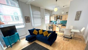 Uma sala de estar moderna com um sofá azul, um tapete preto e um aparador verde-água.
