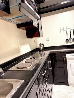A kitchen with a stove, sink, and a coffee maker. - Cozy 1-bedroom studio in gorgeous Giza Governorate with AC (Giza Governorate)