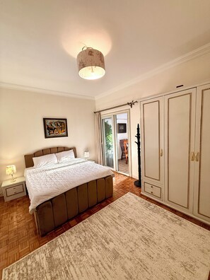 Une chambre à coucher avec un lit, des tables de chevet, une armoire et une fenêtre avec des rideaux.