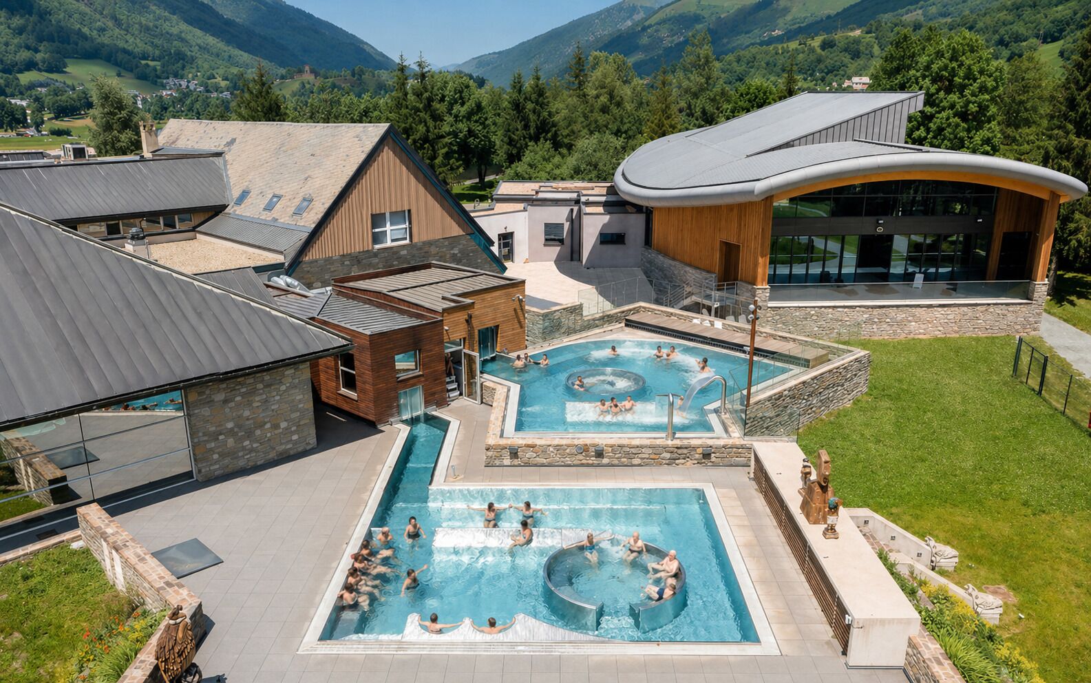 Un resort moderno con varias piscinas, un área de spa y un edificio grande con techo curvo.