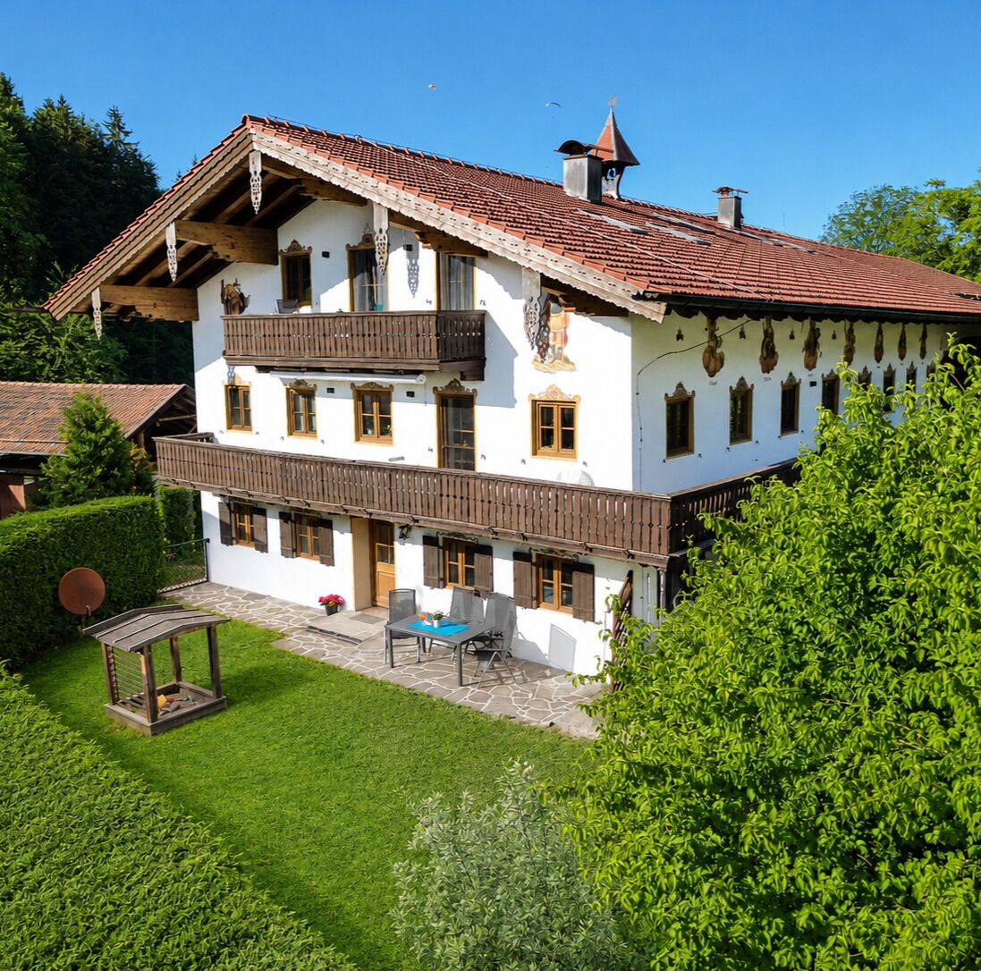 A two-story building with a balcony, a stone patio, and a well-maintained lawn.