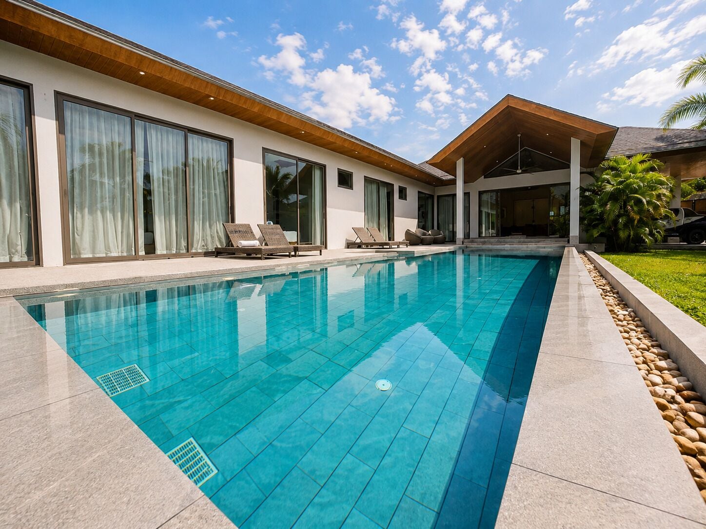 A modern house with a swimming pool, large windows, and a covered outdoor area.