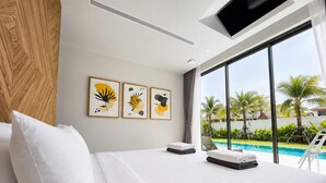 A hotel room with a bed, artwork on the wall, and a view of a swimming pool. - Kamala Grand Estate 5BR Pool Villa (Tambon Kamala)