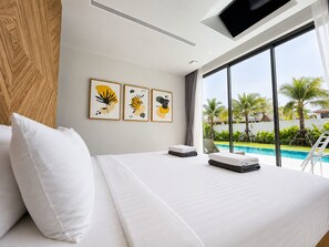 Ein Hotelzimmer mit einem Bett, Kunstwerken an der Wand und Blick auf einen Pool.
