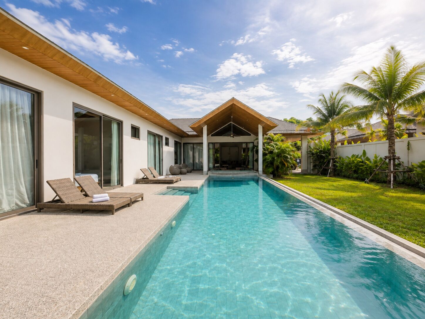 A modern poolside area with lounge chairs, a clear pool, and a covered seating area.