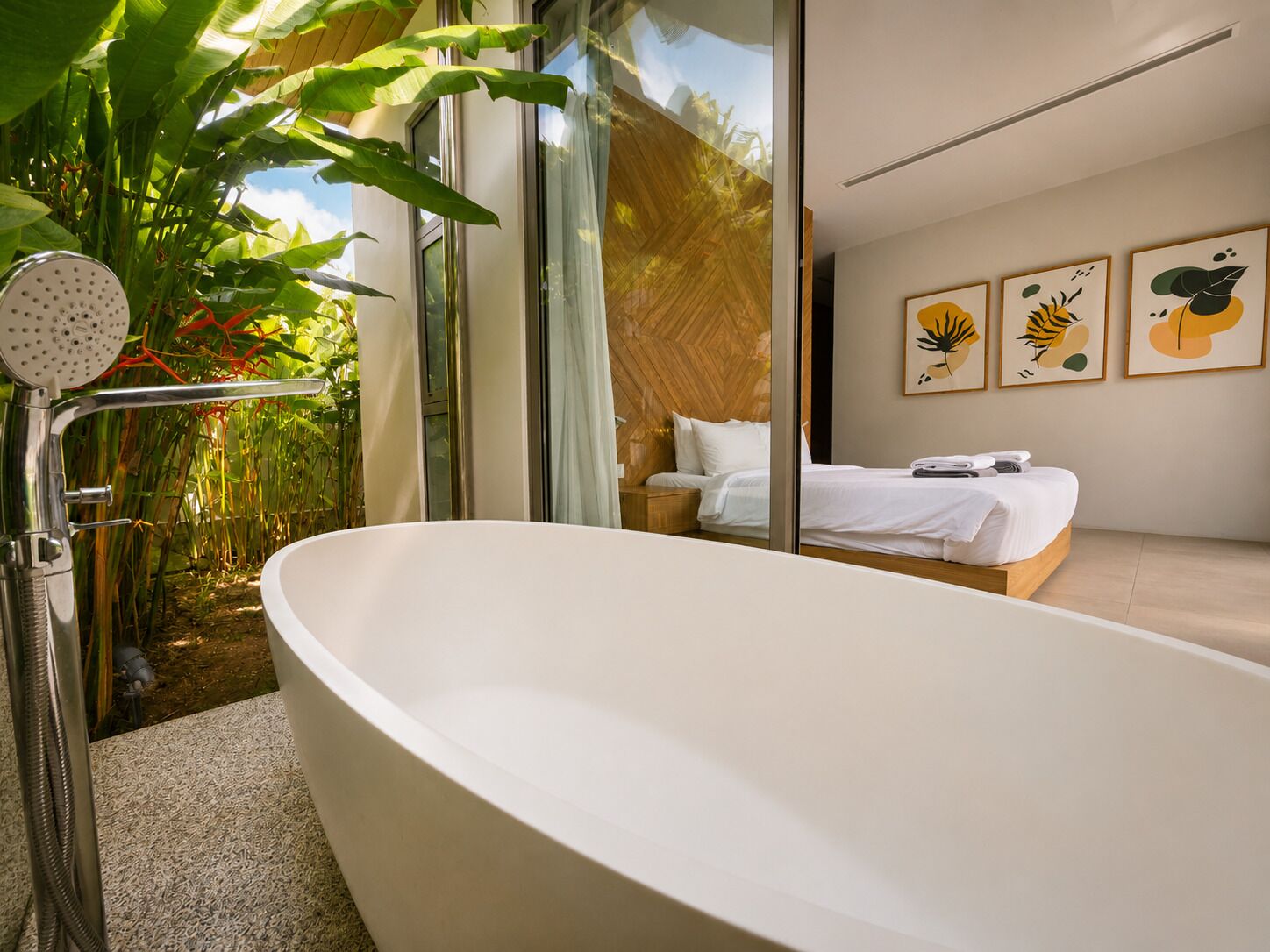 A modern bathroom with a freestanding bathtub, a shower with a handheld showerhead, and a large window overlooking a garden.