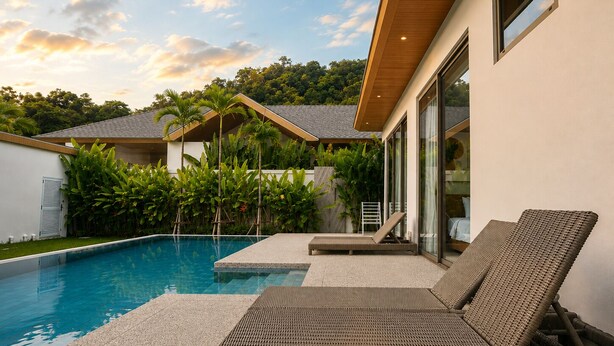 A modern house with a swimming pool, outdoor furniture, and lush greenery. - Kamala Grand Estate 5BR Pool Villa (Tambon Kamala)
