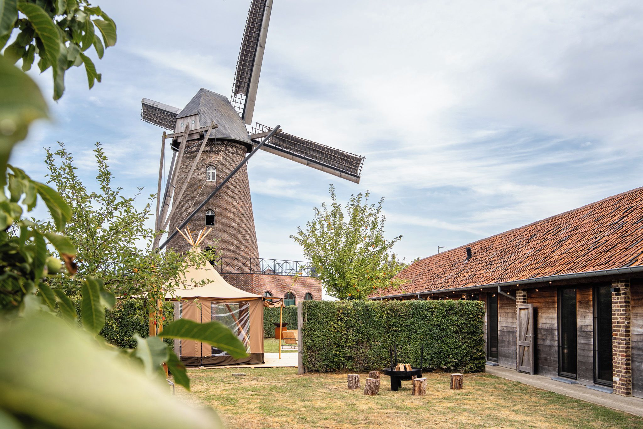 Een klassieke windmolen, een overdekt terras en een gebouw met een pannendak.