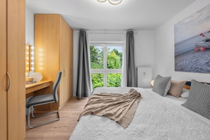 A bedroom with a bed, a desk with a chair, a wardrobe, and a window with curtains. - Frische Brise Vacation Rental—Your Vacation Just 100 Meters from the Beach (Schönberg (Holstein))