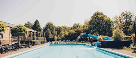 Una piscina con sillones de descanso y un tobogán de agua.
