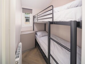 A bunk bed room with a window, a radiator, and a small desk.