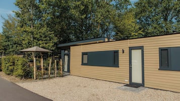 A modern building with a gravel driveway, a covered outdoor seating area, and a door with a window.