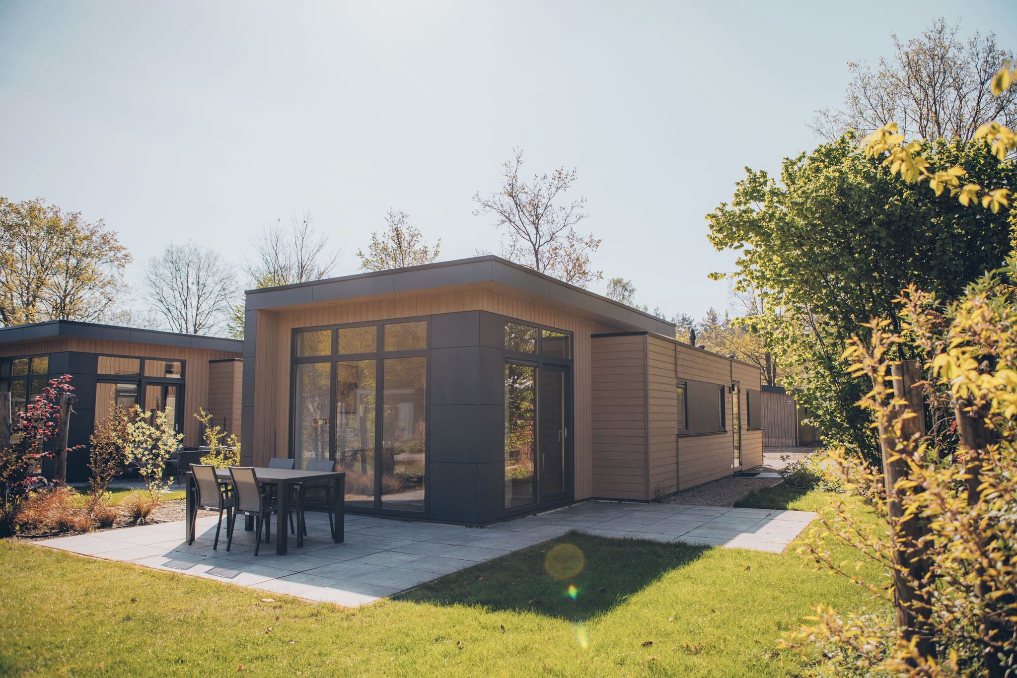 Een modern huis met een terras, een eethoek en een groot raam.