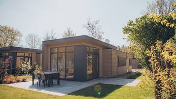 Een modern huis met een terras, een eethoek en een groot raam.