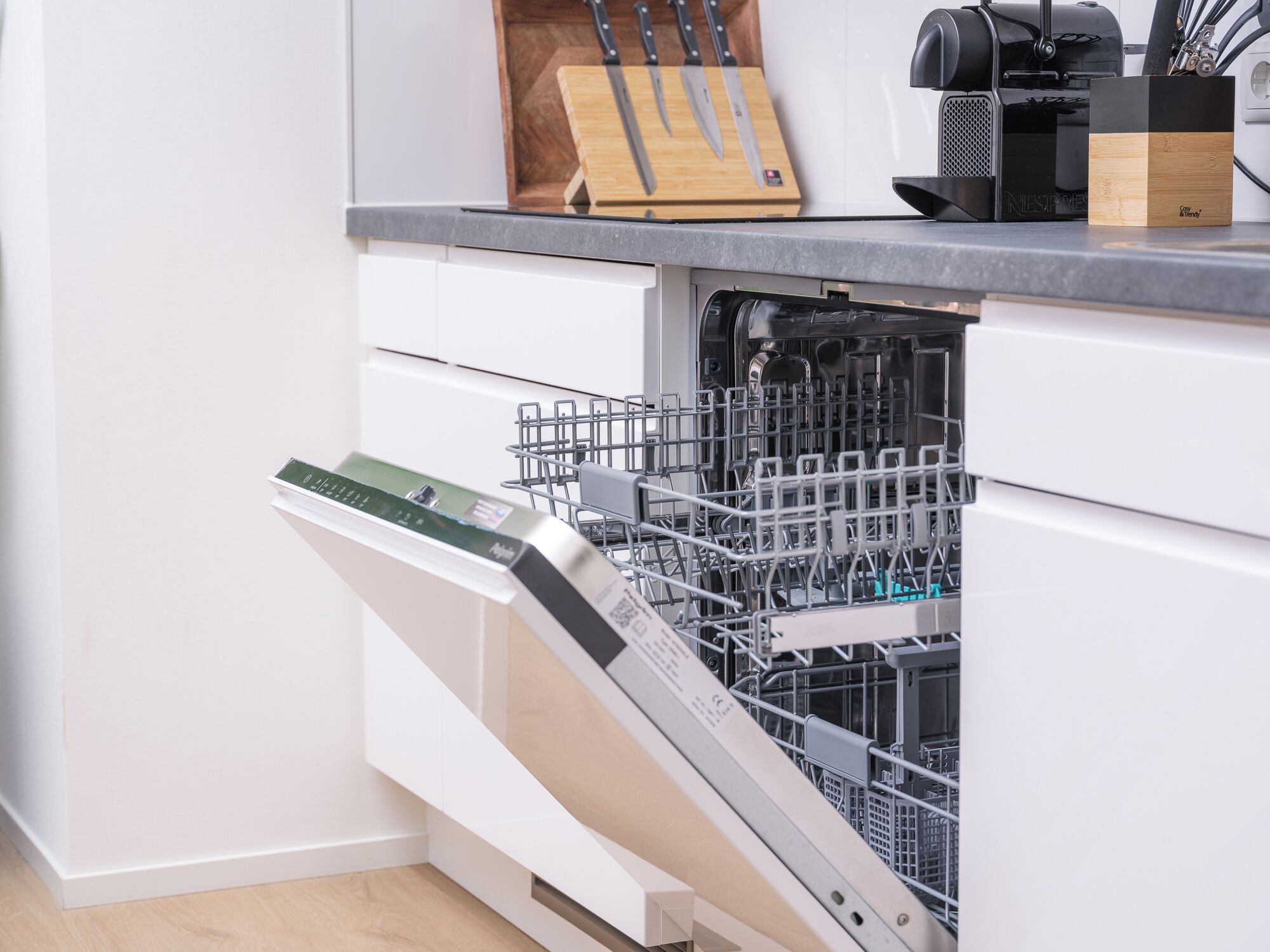 Eine moderne Küche mit Geschirrspüler, Messerblock und Kaffeemaschine.