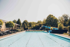 Una piscina con sillones de descanso y un tobogán de agua.