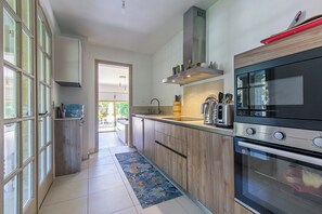 Une cuisine moderne avec des meubles en bois, une cuisinière en acier inoxydable et un four encastré.
