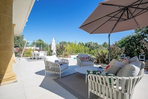Eine Terrasse im Freien mit Essgruppe, einer Couch und einem Sonnenschirm.