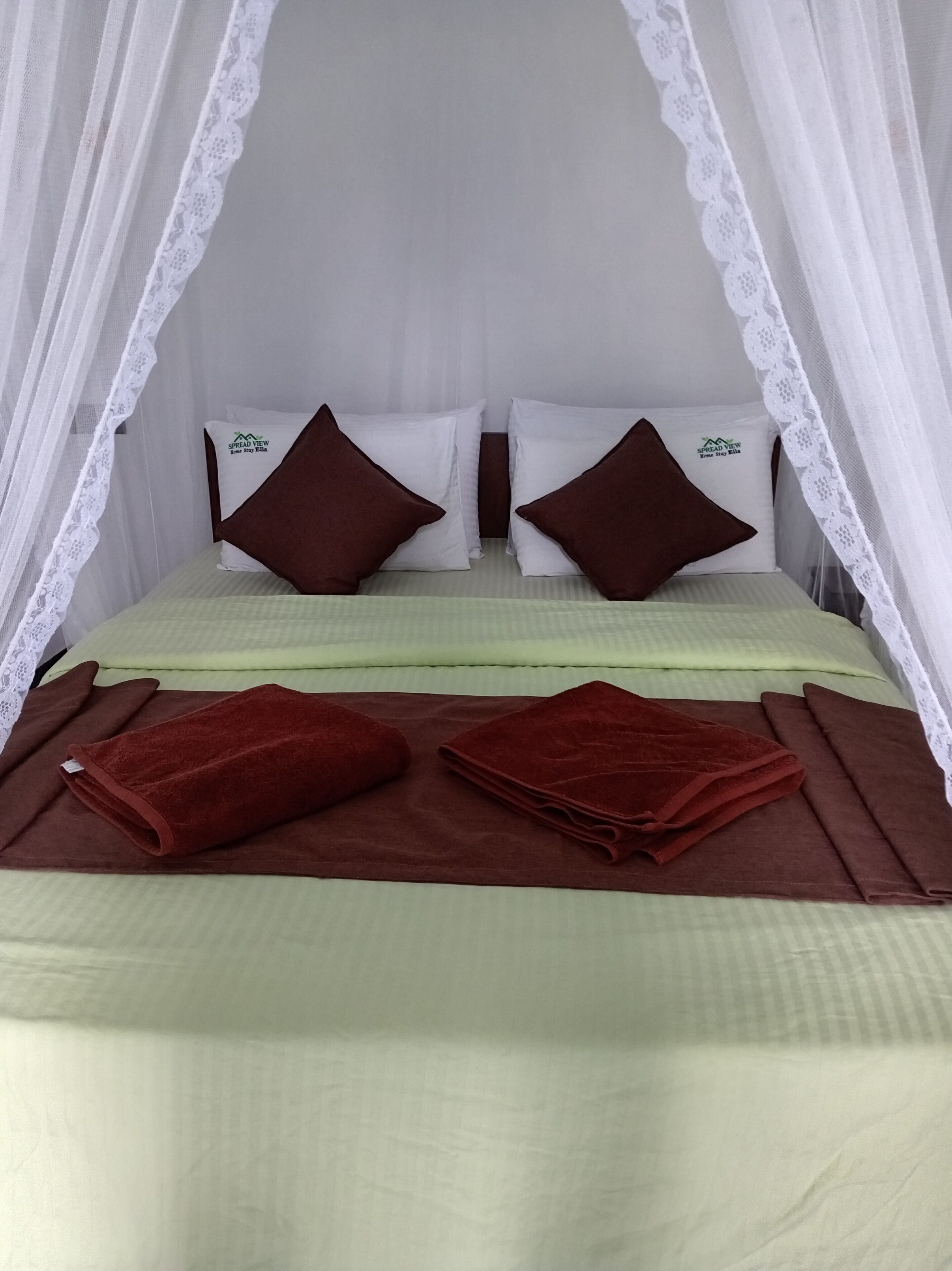 Un lit à baldaquin, avec des oreillers et une couverture pliée.