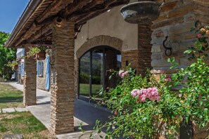 A stone building with a rustic facade, a large arched doorway, and hanging flower baskets.