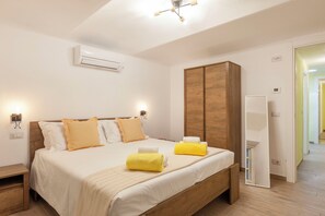 A hotel room with a bed, a wardrobe, an air conditioning unit, and a mirror.