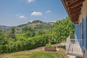 A balcony with a view of a lush green landscape, a wooden structure, and a clear sky. - Villa Bricco Verde 6BR Luxury Countryside Retreat (Santo Stefano Belbo)