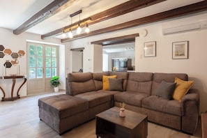 A modern living room with a sectional sofa, a coffee table, and a dining area visible through an open door. - Villa Bricco Verde 6BR Luxury Countryside Retreat (Santo Stefano Belbo)