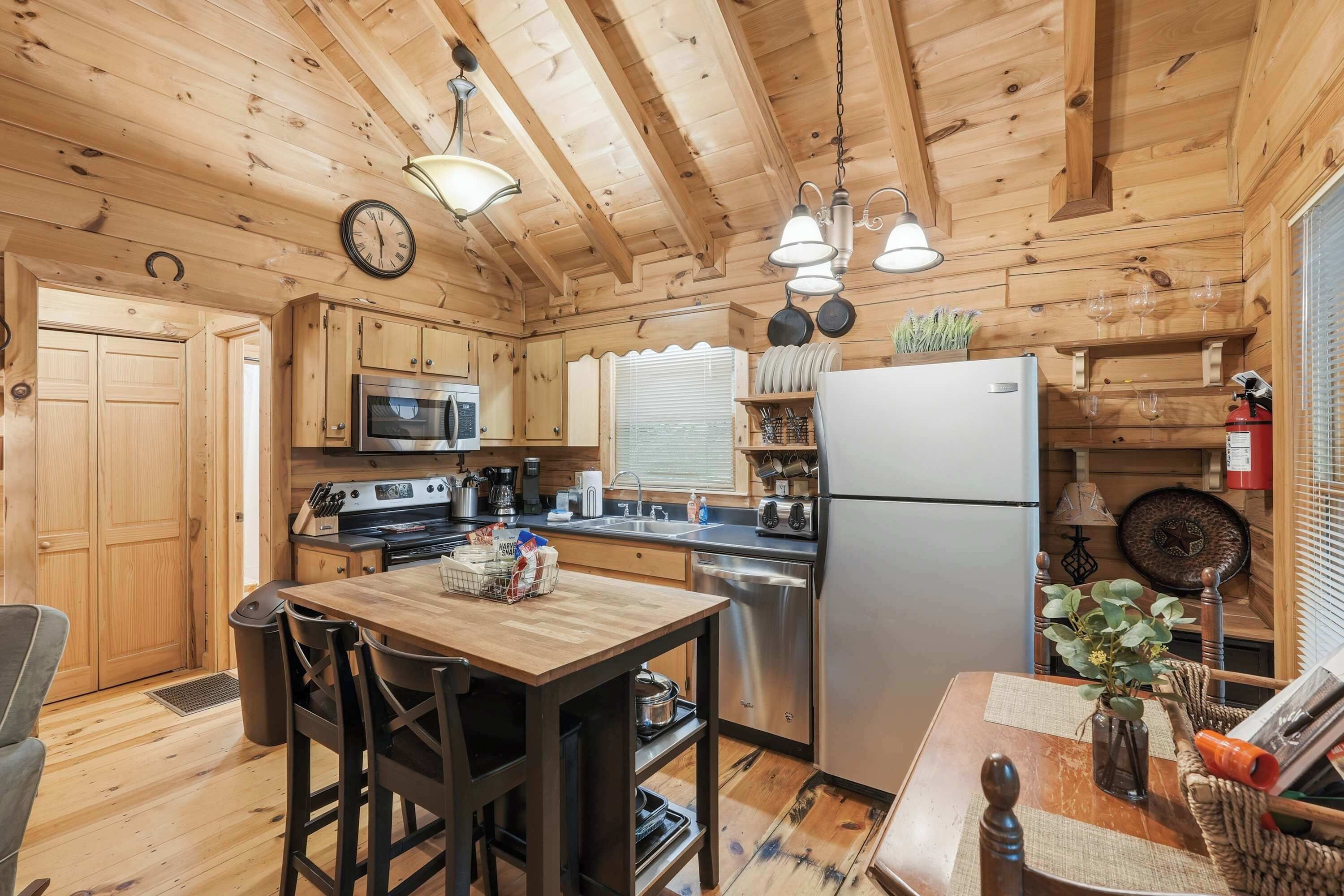 Cocina de cabaña de madera con una mesa de comedor, sillas, refrigerador, estufa, microondas y lámparas colgantes.