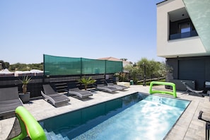 Ein Swimmingpool mit Liegestühlen und einer grünen aufblasbaren Rutsche.