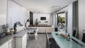 A modern living room with a sofa, a flat-screen TV, and a foosball table. - Apartment Dorota with private Pool near Fažana (Pula)