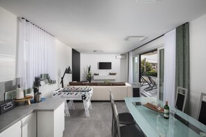 Ein modernes Wohnzimmer mit einer Couch, einem Flachbildfernseher und einem Kicker.