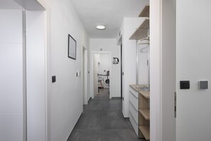 Ein schmaler Flur mit Waschmaschine, Wäscheständer und einer kleinen Küchenzeile mit Arbeitsplatte und Schränken.