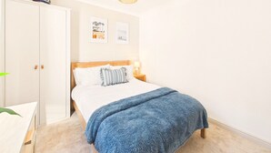 A bedroom with a bed, a wardrobe, a bedside table, and a lamp. - Coastal Charm | 4BR House | near St Ives Harbour (St Ives)