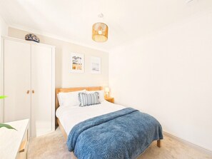 A bedroom with a bed, a wardrobe, a bedside table, and a lamp. - Coastal Charm | 4BR House | near St Ives Harbour (St Ives)