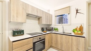 A modern kitchen with wooden cabinets, a built-in oven, a microwave, and a toaster. - Coastal Charm | 4BR House | near St Ives Harbour (St Ives)