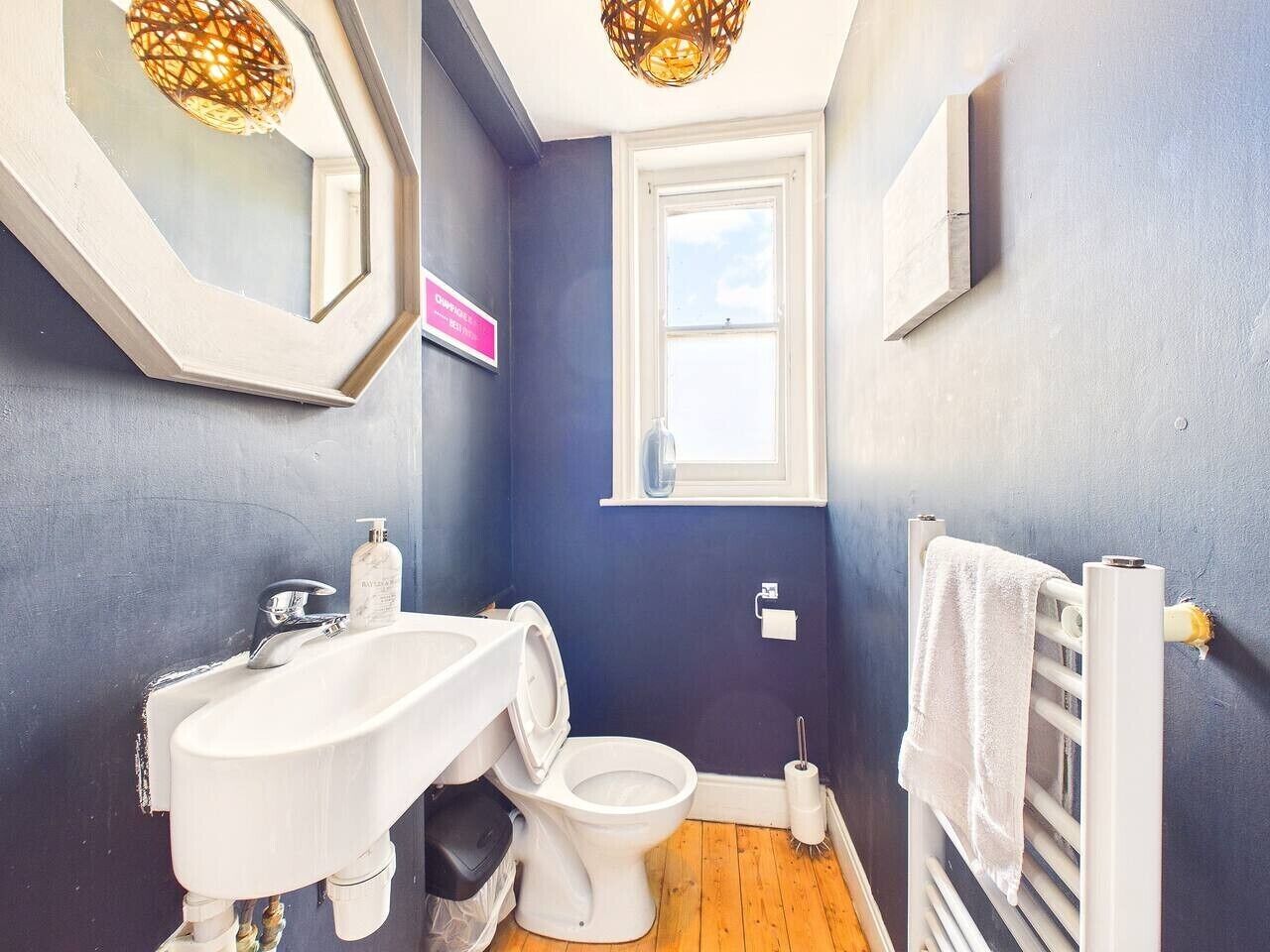 Ein Badezimmer mit weißem Waschbecken, Toilette, Handtuchhalter und einem Fenster.