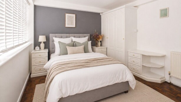 Un dormitorio con cama, mesitas de noche, cómoda y radiador.