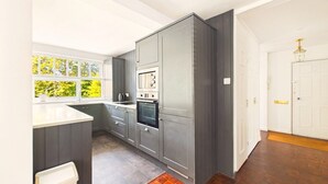 Una cocina con armarios grises, una encimera blanca y una ventana con vistas a árboles.