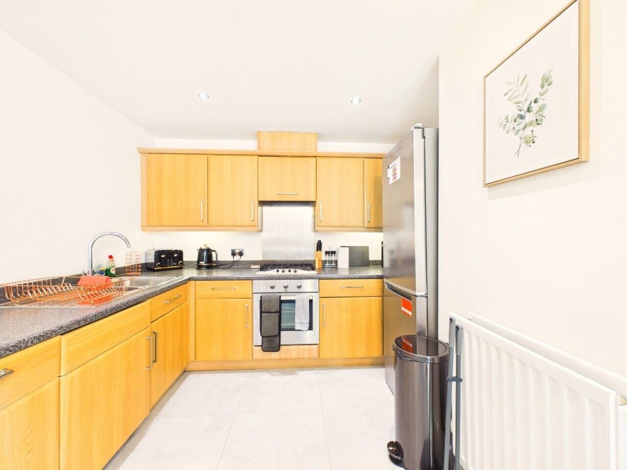 A modern kitchen with wooden cabinets, a stainless steel refrigerator, and a built-in oven.