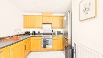 A modern kitchen with wooden cabinets, a stainless steel refrigerator, and a built-in oven.
