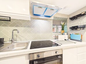 A modern kitchen with a built-in stove, a sink, and a ventilation hood.